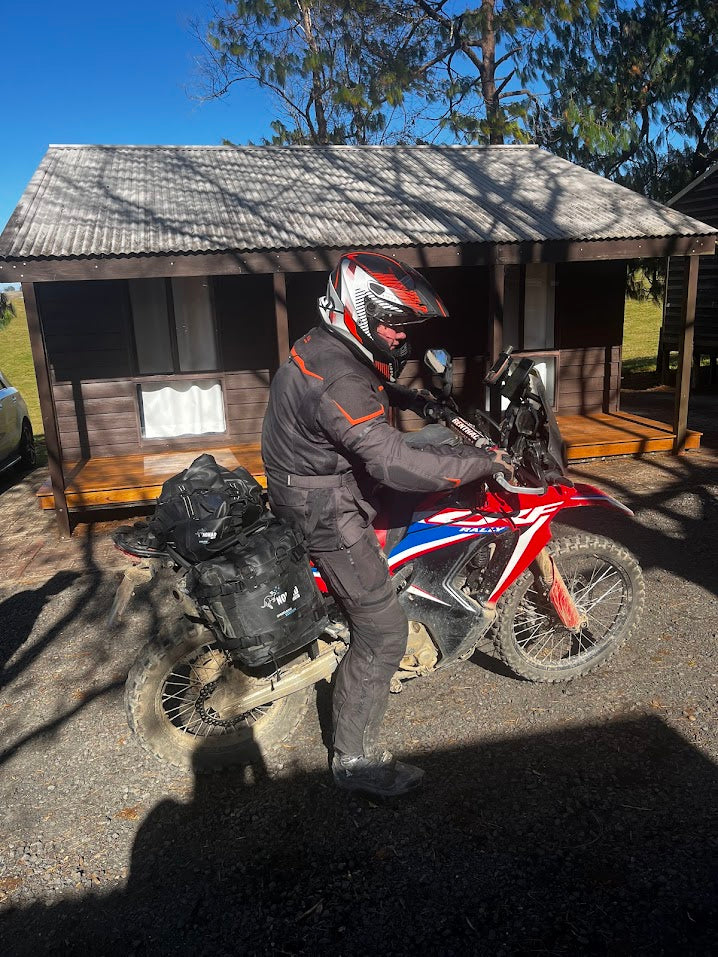 Rider in helmet on red bike near cabin house