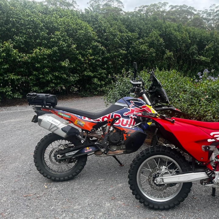 Nomad Moto KTM 890 Red and black dirt bike with 'Red Bull' branding on a paved road with greenery in the background.